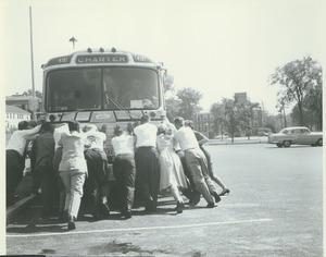 Alumni Medal recipients and family pushing a bus during Centennial Alumni weekend