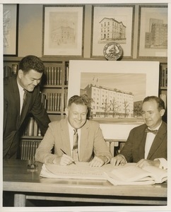 Willis C. Gorthy signing paperwork at a presentation of prospective building plans