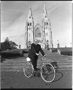 Cardinal Tomás Ó Fiaich, Primate of all Ireland (Catholic Church), sitting on a bicycle in front of Armagh Cathedral