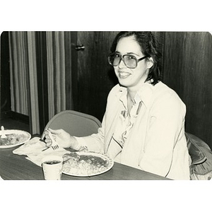 Portrait of a woman with a plate of food at a community meal.