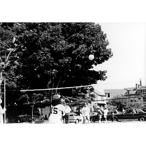 Volleyball game on a tree-shaded court.