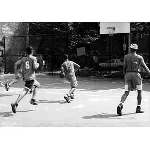 Young men playing basketball in a Villa Victoria neighborhood park.