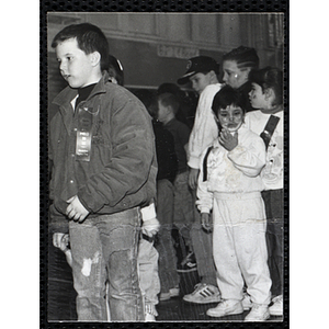 A boy wearing a ribbon walks past while the boy behind him looks at his hand at a joint Charlestown Boys & Girls Club and Charlestown Against Drugs (CHAD) event