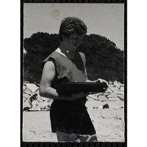 A teenage boy holds a radio on a beach