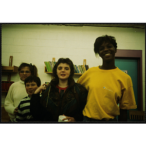 Two youth and two women stand in front of a bookshelf at a Tri-Club event