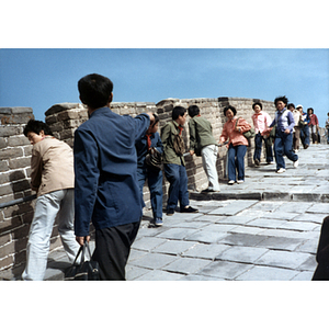 Man points while standing among others on the Great Wall of China
