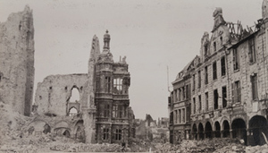 Cyclist pedaling through a street with a destroyed church on one side and badly damaged buildings on the other, Arras