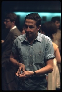 Artist Robert Rauschenberg, in front of a 16mm projector at a reception