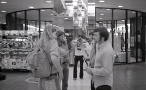 Commune member distributing Free Spirit Press in an indoor shopping mall: self-portrait of photographer photographing a group talking about the magazine