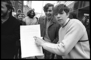 Teenaged boy points to a copy of a joint peace treaty during a demonstration against the invasion of Laos