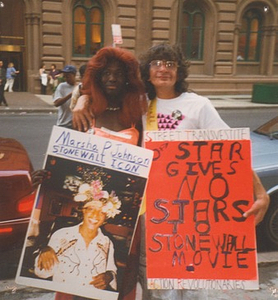 A Photograph of Sylvia Rivera with Cocoa Rodriguez Holding Stonewall Posters Protesting the 1996 Stonewall Film Premiere