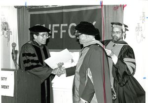 Suffolk University Professor Daniel H. Perlman shaking hands with Malcolm Forbes, and Dean Richard McDowell at the 1987 commencement