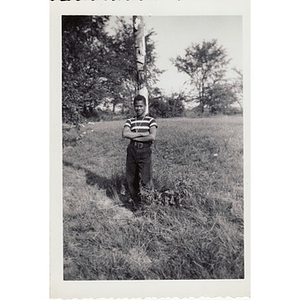 Boy leans against a totem pole in a field at Breezy Meadows Camp