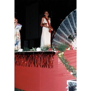 A young woman in a long white dress stands on the stage during the Festival Betances beauty contest.