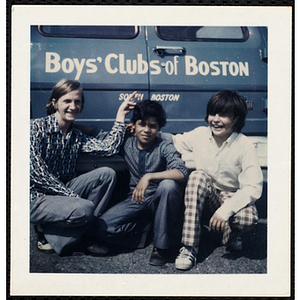 Three boys pose in front of a car with "Boys' Clubs of Boston South Boston" sign