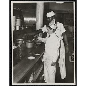 A member of the Tom Pappas Chefs' Club works in a kitchen with a cook