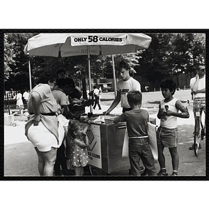 A teenage boy operating an ice juice cart waits on children on Boston Common