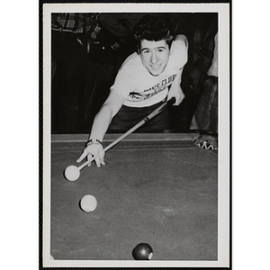 A Boy smiles as he takes his shot in a pool game