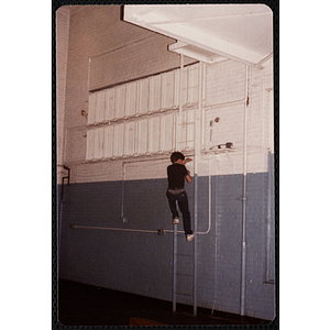 A boy climbs a ladder on the wall of the Charlestown gymnasium