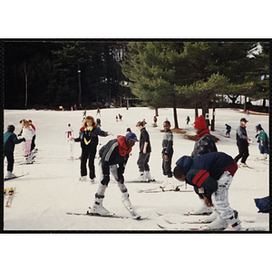 A group of boys receive ski instruction from a woman at a resort