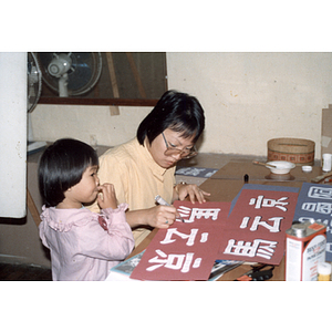 Woman works on a Mel King campaign sign in Chinese with her daughter next to her, in preparation for the August Moon Festival in Boston's Chinatown