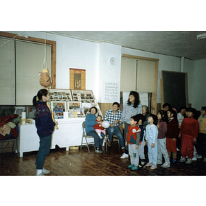 Woman addresses a group of children who await their turns at a piñata during a Chinese Progressive Association Christmas party