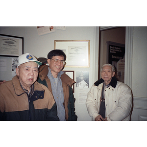 Chinese Progressive Association members at a meeting, walk in front of a wall with veterans' honors