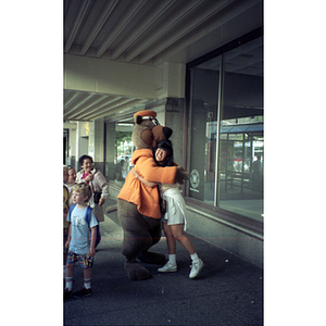 Chinese Progressive Association member hugging a bear mascot on a trip to Vancouver