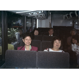 Chinese Progressive Association members sit on a charter bus and smile