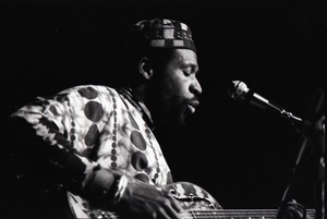 Taj Mahal in concert at Northfield, Mass.: Taj Mahal seated, playing steel guitar