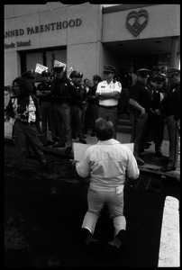 Pro-life protester on his knees, facing a line of police in front of the Providence Planned Parenthood clinic