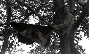 Gay liberation demonstration at Cambridge Common: man hanging Gay Liberation Front flag