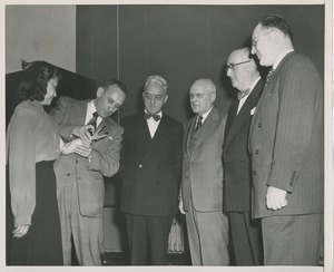 Five men examining a woman's artificial arm