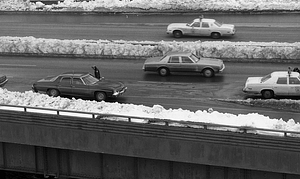 Police officer walking among cars on snowy highway in Boston