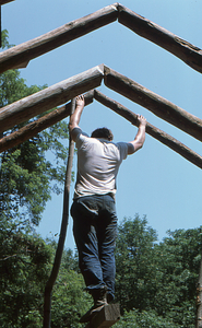 Peter Jensen holding up third pair of rafters at the Moon Barn Raising at entrance to Hopkins Forest on 2 August 1975.