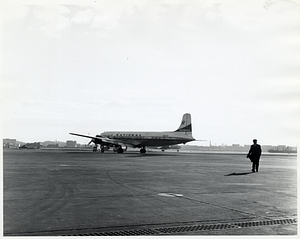 Unidentified man in uniform walking away from National Airlines plane, likely at Logan Airport