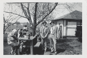People sitting and standing around a picnic table
