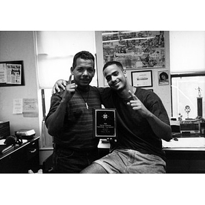 Inquilinos Boricuas en Acción staffer Ralph Ortiz poses with a young man and their paddleball tournament trophy.