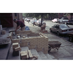 Workman creating a brick divider on the front steps of the Jorge Hernandez Cultural Center.