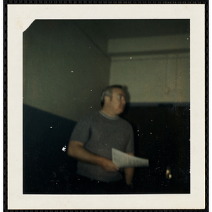 A male staffer of the South Boston Boys' Club holding a document, facing right