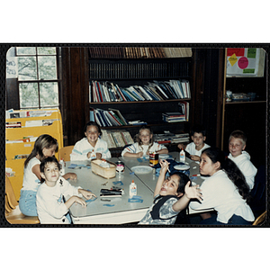 A group of six girls and two boys sitting around a table, working on projects for their arts and crafts class at the Charlestown Boys & Girls Club