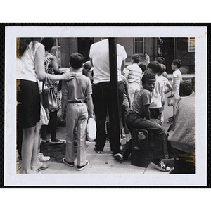 Boys gather on a sidewalk with suitcases and bags