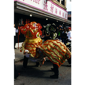 Two men wear a dragon costume in the street during a celebration of the Chinese New Year