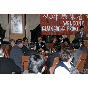 Members of the Chinese Progressive Association and the Guangdong Province delegation sit together while a man speaks from a nearby podium