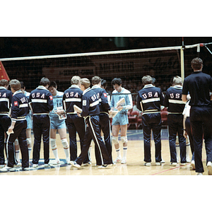 Members of the USA and China volleyball teams stand on either sides of a volleyball net