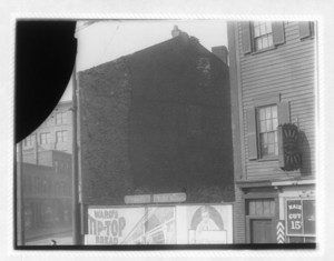 View of a billboard between two buildings, one of which hosues a barbershop