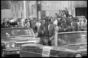 Robert F. Kennedy (left) and Walter Mondale riding in an open car at the Turkey Day parade while stumping for Democratic candidates in the northern Midwest