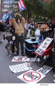 Occupy Wall Street: demonstrator in a Guy Fawkes mask raising his fist next to a demonstrator raising American and Puerto Rican flags