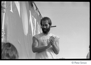 John Hall clapping on stage in front of a No Nukes banner at the No Nukes concert and protest, Washington, D.C.