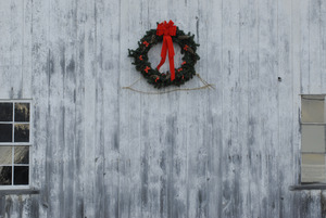 Christmas wreath hung on the side of a barn